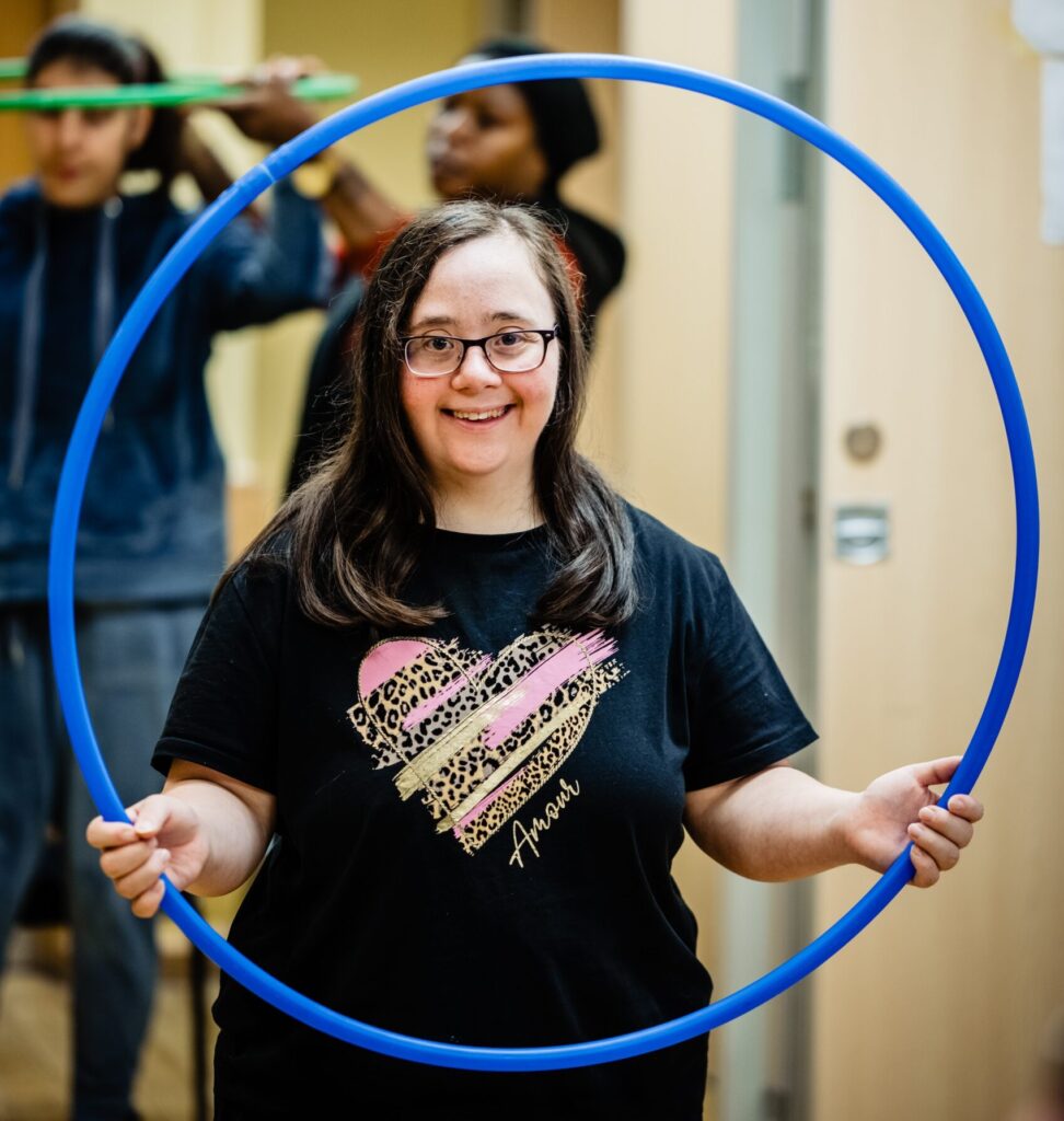 Person we support smiling at camera, holding a hoola hoop